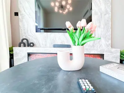 a vase of pink tulips on a table with a remote control at City Views & Comforts at Binghatti Corner in Dubai
