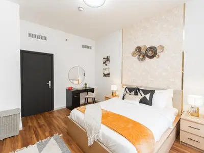 a bedroom with a large bed and a desk at Serene 1BR in Diamond Views 3 JVC - Pool Access & Peaceful Living , Managed by Think Realty in Dubai