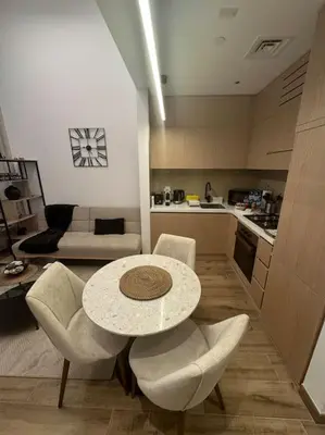 a living room with a table and chairs and a kitchen at Luxury Studio apartment in JVC, Oakley Square Residences in Dubai