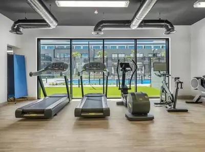 a gym with cardio equipment and a large window at Luxury Studio apartment in JVC, Oakley Square Residences in Dubai