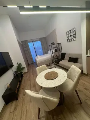 a living room with a table and chairs and a couch at Luxury Studio apartment in JVC, Oakley Square Residences in Dubai