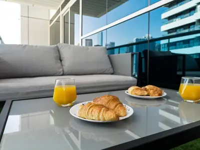 two plates of croissants and orange juice on a glass table at Spacious Home Near Metro & Beach in Dubai Marina in Dubai