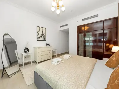a bedroom with a bed and a dresser and a mirror at Spacious Home Near Metro & Beach in Dubai Marina in Dubai