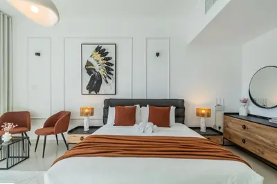 a bedroom with a large bed and two chairs at ShoresInn - Aesthetic Stay with Dubai Marina View in Dubai