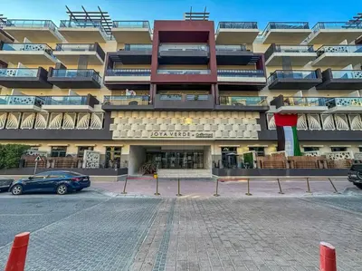 a large building with a parking lot in front of it at Serene Studio APT with Pool and Gym in Dubai