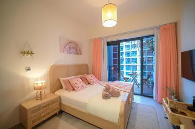a bedroom with a bed with pink pillows and a window at UrbanHomes - Cozy, Wooden and Travel Eco-Friendly Studio in Dubai