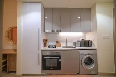 a kitchen with a stove and a washer and dryer at UrbanHomes - Cozy, Wooden and Travel Eco-Friendly Studio in Dubai