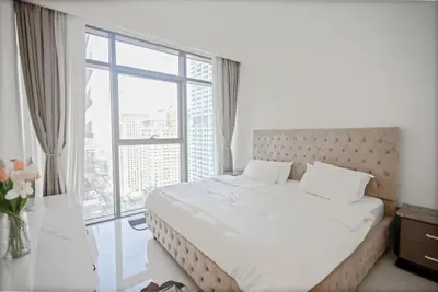 a bedroom with a white bed with a large window at Emaar Beachfront Luxe Retreat in Dubai