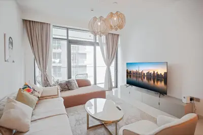 a living room with a couch and a tv at Emaar Beachfront Luxe Retreat in Dubai