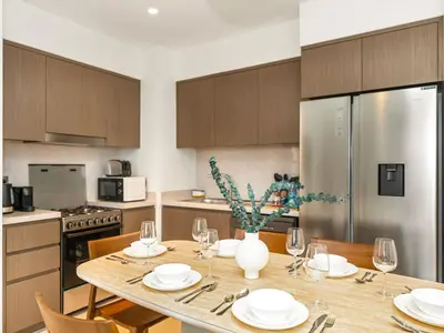 a kitchen with a wooden table with plates and wine glasses at UrbanStays Dubai - Act Tower in Dubai