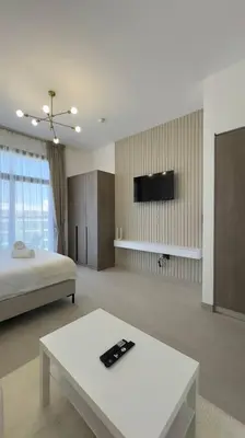 a room with a bed and a table and a tv at New! Modern cosy Studio Laya Heights in Dubai