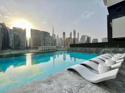 a large swimming pool with a city in the background at Binghatti Canal Business Bay in Dubai