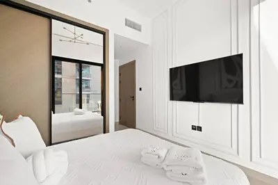 a white bedroom with a large mirror and a bed at Binghatti Canal Business Bay in Dubai