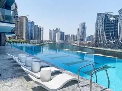 a large swimming pool with white lounge chairs in front of a city at Binghatti Canal Business Bay in Dubai
