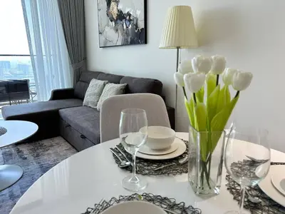 a living room with a table with a vase of flowers at Elegant 1br Escape Jvc Pool & Balcony Access in Dubai