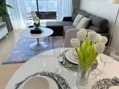 a living room with a table with a vase of flowers on it at Elegant 1br Escape Jvc Pool & Balcony Access in Dubai