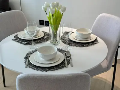 a white table with plates and glasses and flowers on it at Elegant 1br Escape Jvc Pool & Balcony Access in Dubai