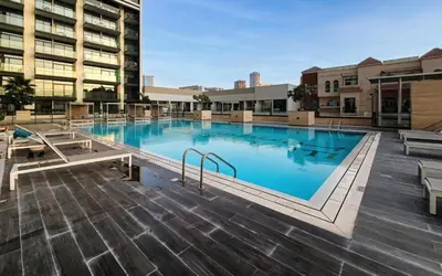 a large swimming pool in the middle of a building at Modern Luxury Fully Furnished 1BH Apartment in Binghatt Emerald JVC - Easy Access to JBR, Circle Mall & Dubai Hills Mall in Dubai