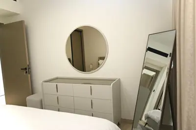 a bedroom with a white dresser and a mirror at Modern Luxury Fully Furnished 1BH Apartment in Binghatt Emerald JVC - Easy Access to JBR, Circle Mall & Dubai Hills Mall in Dubai