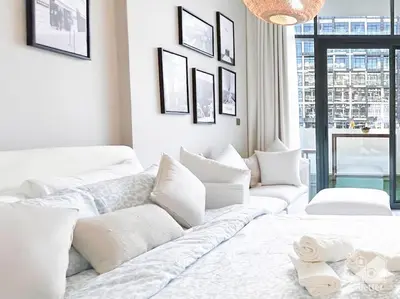 a white living room with a large white couch at Meydan Bliss Luxurious Studio with Private Balcony in Dubai