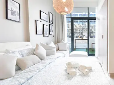 a white bedroom with a large bed with two towels on it at Meydan Bliss Luxurious Studio with Private Balcony in Dubai