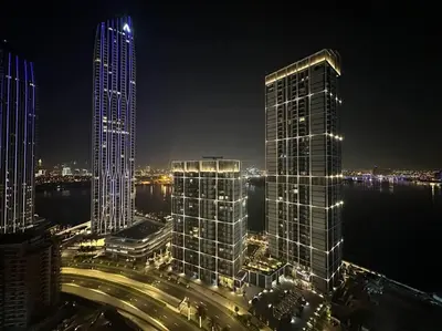 a night view of a city with tall buildings at Luxurious 3BR - Pool - Canal View - Kids Play Area in Dubai