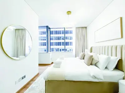 a white bedroom with a large bed and a mirror at Stunning 2 bedrooms in Sky Gardens DIFC in Dubai