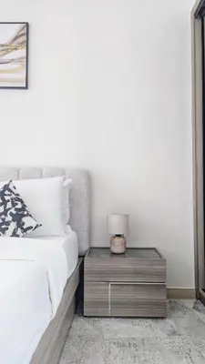 a bedroom with a bed and a table with a lamp at Modern Luxury Fully Furnished 1BH Apartment in Binghatt Heights JVC - Easy Access to JBR, Circle Mall & Dubai Hills Mall in Dubai