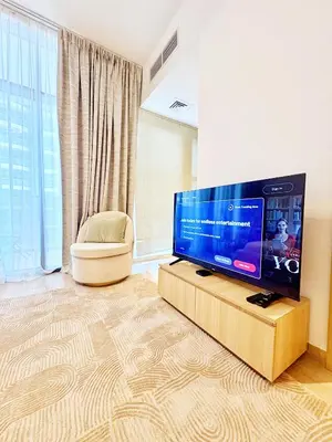 a living room with a large flat screen tv at Cozy Studio JVC Dubai, Short Drive to Dubai Marina, JBR, Downtown Dubai in Dubai