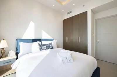 a bedroom with a large white bed with towels on it at 2Bed-400m from Burj Khalifa- Heart of Dubai in Dubai