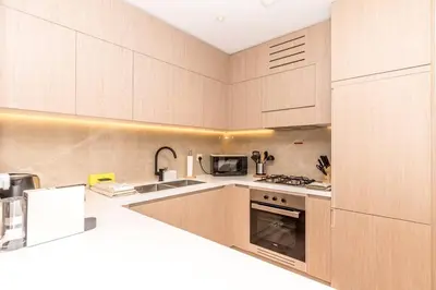 a kitchen with wooden cabinets and a stove top oven at Luxury Apartment in Oakley Square Residences, JVC in Dubai