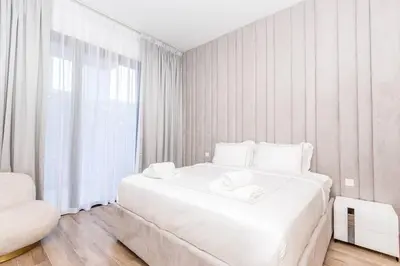 a white bedroom with a large white bed and a window at Luxury Apartment in Oakley Square Residences, JVC in Dubai