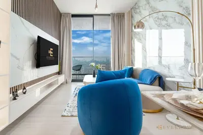 a living room with a blue chair and a tv at 1BR Gem in JVC Pool, Gym, BBQ & Balcony in Dubai
