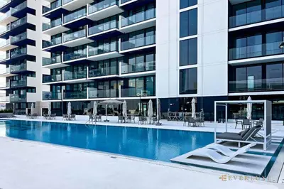 a swimming pool in front of a large building at 1BR Gem in JVC Pool, Gym, BBQ & Balcony in Dubai