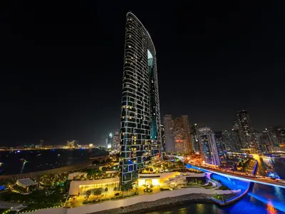 a tall building at night with a city at Brand New! Dubai Eye & JBR Beach Panorama! in Dubai
