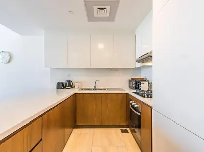 a kitchen with white cabinets and a wooden floor at Elegant One Bed Apartment - Hameni Tower,JVC in Dubai