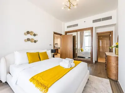 a white bedroom with a large white bed with yellow pillows at Elegant One Bed Apartment - Hameni Tower,JVC in Dubai