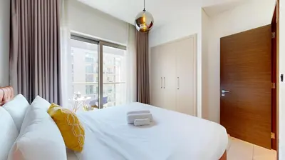 a bedroom with a white bed and a large window at Locations I Creek Vistas Reserve I Luxury Calm 1BR I 12 Min Drive to Downtown Dubai & Business Bay I Modern Comfort in Meydan Community in Dubai
