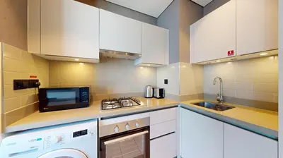 a kitchen with white cabinets and a washer and dryer at Locations I Creek Vistas Reserve I Luxury Calm 1BR I 12 Min Drive to Downtown Dubai & Business Bay I Modern Comfort in Meydan Community in Dubai