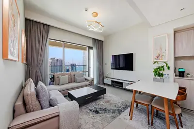 a living room with a couch and a tv at Vida Creek Beach 1 Bedroom in Dubai