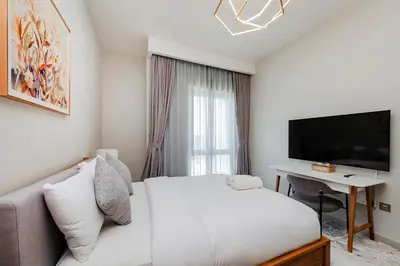 a bedroom with a bed and a desk and a television at Vida Creek Beach 1 Bedroom in Dubai