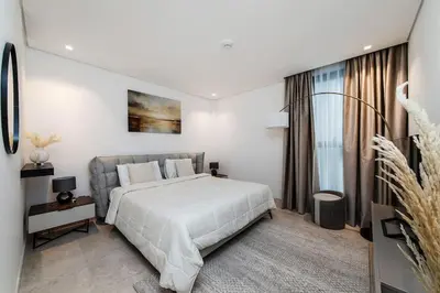 a white bedroom with a large bed and a window at Burj Khalifa View 3bedroom in Dubai