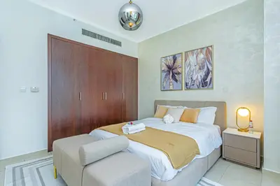 a bedroom with a large bed and a chair at Savis Homes - Luxury 2 Bedroom Suite with Full Burj Khalifa View in Dubai
