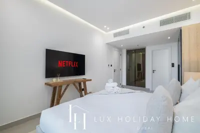 a bedroom with a bed and a tv on a wall at LUX The Majara Marina View Suite in Dubai