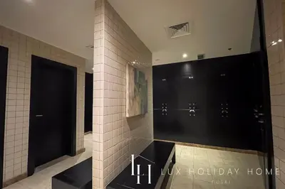 a bathroom with a black door and a tile wall at LUX The Majara Marina View Suite in Dubai