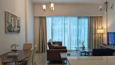 a living room with a couch and a dining room at Fully Furnished 1BR In Montrose Tower B Dubai, Close by Dubai Science Park, Dubai Miracle Garden, Dubai Hills Mall in Dubai