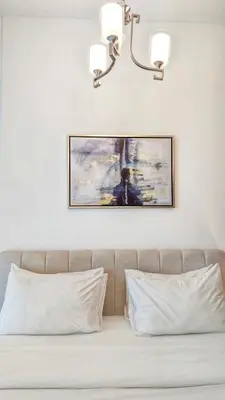 a picture hanging above a bed with white pillows at Fully Furnished 1BR In Montrose Tower B Dubai, Close by Dubai Science Park, Dubai Miracle Garden, Dubai Hills Mall in Dubai
