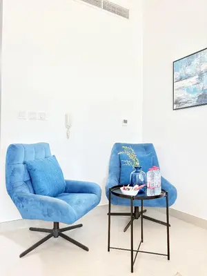 a blue chair and a table in a room at Elegant Studio Stay near Miracle Garden, Butterfly Garden & Dubai Hills Mall in Dubai