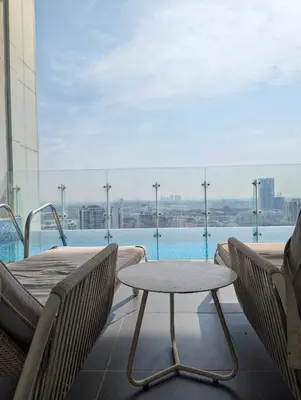a balcony with a table and chairs and a pool at Fully Furnished 1BR Close by Dubai Science Park, Dubai Miracle Garden, Dubai Hills Mall in Dubai