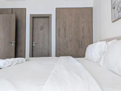 a white bed with two doors in a bedroom at Fully Furnished 1BR Close by Dubai Science Park, Dubai Miracle Garden, Dubai Hills Mall in Dubai